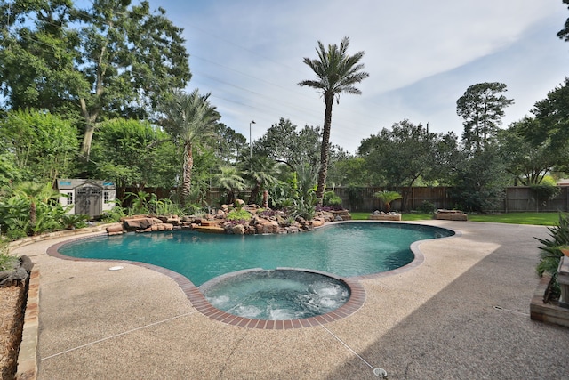 12923 Hunterfield Dr, Cypress, TX 77429 - view of swimming pool with a pool with connected hot tub, a fenced backyard, a storage unit, a patio area, and an outbuilding
