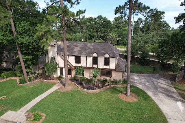 12923 Hunterfield Dr, Cypress, TX 77429 - english style home featuring stucco siding, a shingled roof, concrete driveway, and view of scattered trees