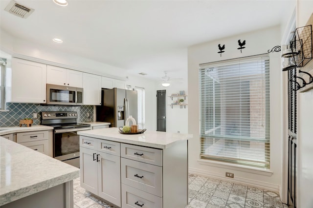6202 Arcadian Shores Dr, Houston, TX 77084 - kitchen featuring appliances with stainless steel finishes, decorative backsplash, light stone counters, recessed lighting, and a kitchen island