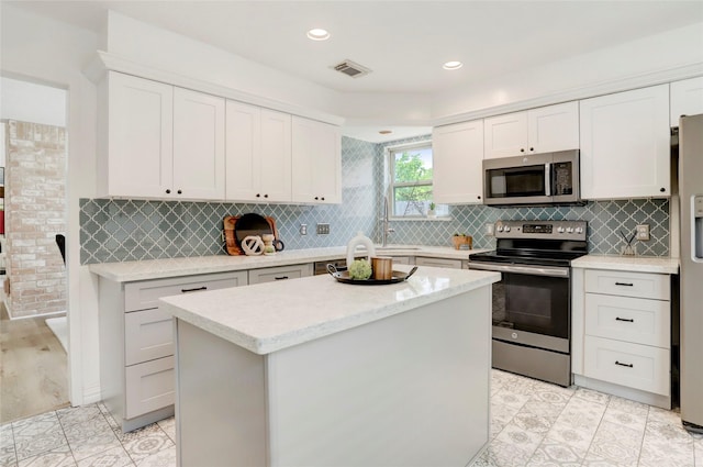 6202 Arcadian Shores Dr, Houston, TX 77084 - kitchen featuring appliances with stainless steel finishes, white cabinetry, a center island, decorative backsplash, and recessed lighting