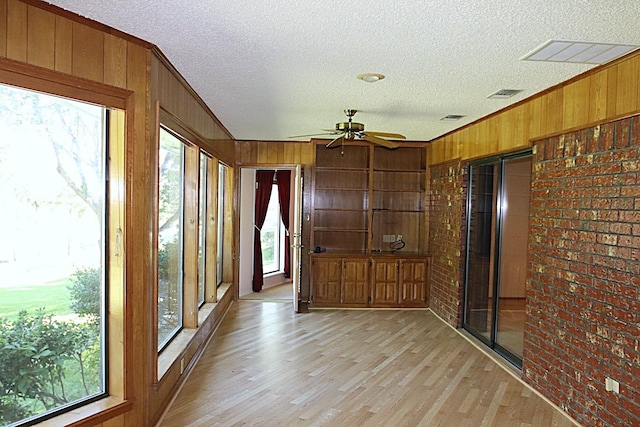 606 County Road 1947, Yantis, TX 75497 - unfurnished sunroom featuring wooden walls, a ceiling fan, healthy amount of natural light, brick wall, and a textured ceiling