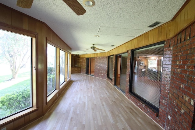 606 County Road 1947, Yantis, TX 75497 - unfurnished sunroom with brick wall, wood finished floors, a textured ceiling, and wood walls