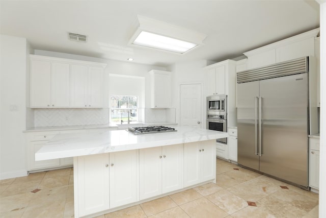 4603 Joyce Blvd, Houston, TX 77084 - kitchen with built in appliances, backsplash, a kitchen island, white cabinets, and light tile patterned floors