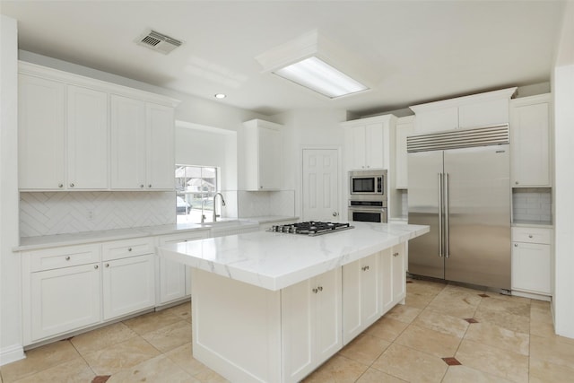 4603 Joyce Blvd, Houston, TX 77084 - kitchen featuring built in appliances, a sink, a kitchen island, backsplash, and white cabinets