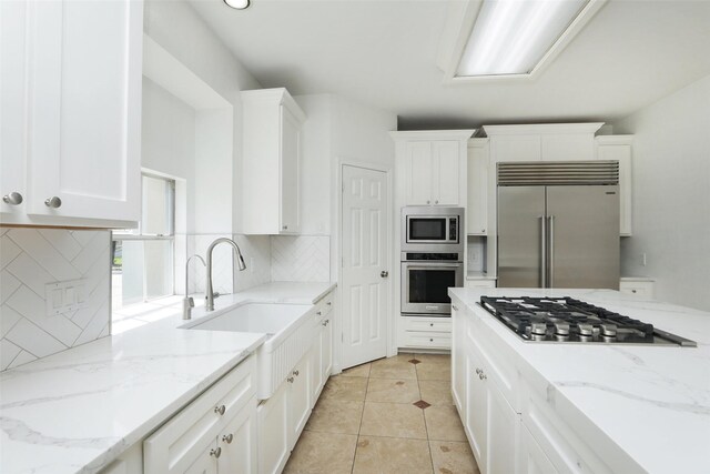 4603 Joyce Blvd, Houston, TX 77084 - kitchen with built in appliances, white cabinets, a sink, backsplash, and light stone countertops