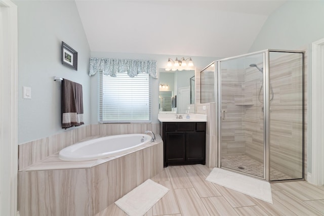 bathroom with vaulted ceiling, a shower stall, a garden tub, vanity, and a chandelier