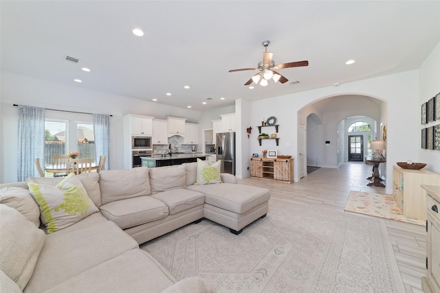 living area with arched walkways, ceiling fan, recessed lighting, and light tile patterned floors