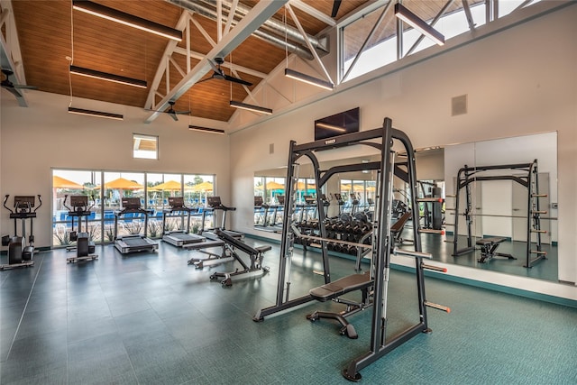 gym with a towering ceiling, wooden ceiling, and beamed ceiling