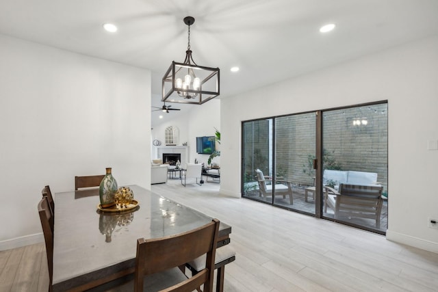 dining space featuring a chandelier, baseboards, a fireplace, light wood finished floors, and recessed lighting
