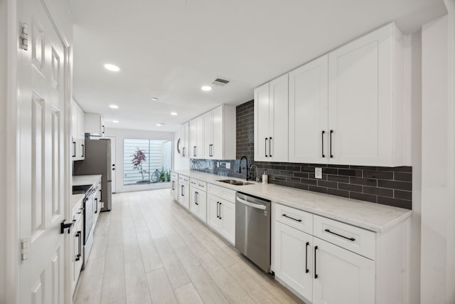 kitchen with dishwasher, a sink, backsplash, white cabinetry, and light wood finished floors