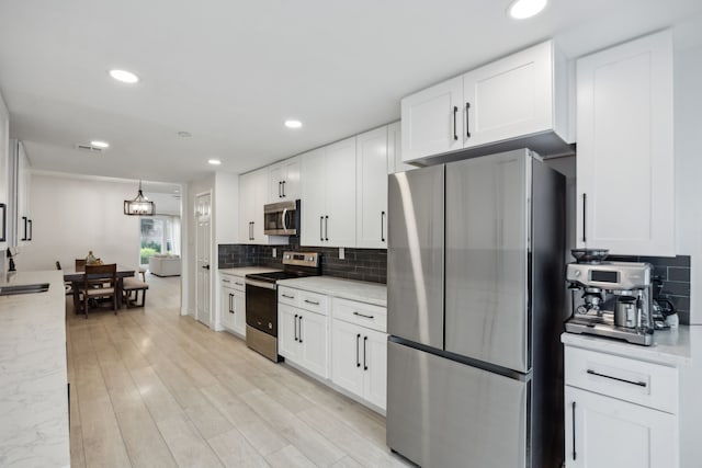 kitchen featuring stainless steel appliances, tasteful backsplash, white cabinets, recessed lighting, and light stone countertops
