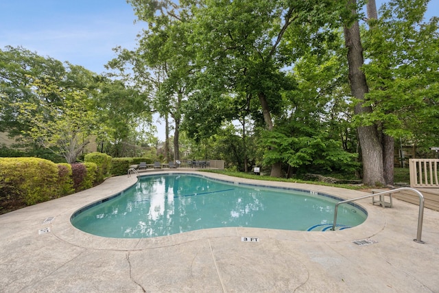 community pool featuring a patio and view of wooded area