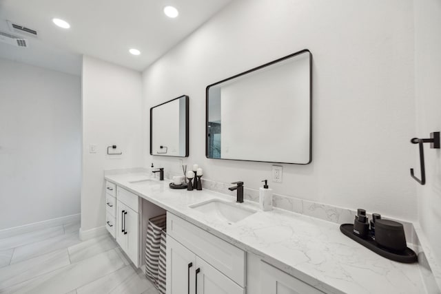 bathroom with double vanity, marble look tile flooring, recessed lighting, and baseboards