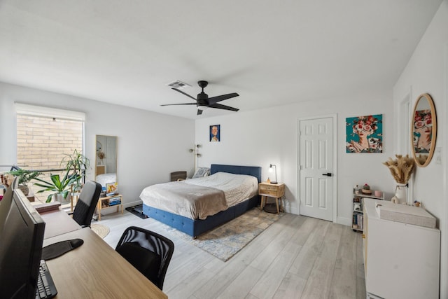 bedroom featuring light wood-style floors, an office area, a ceiling fan, and baseboards