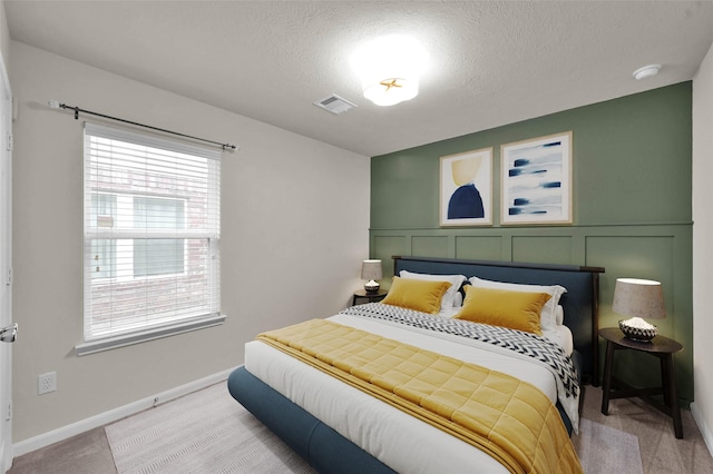 bedroom with light colored carpet, a textured ceiling, and baseboards