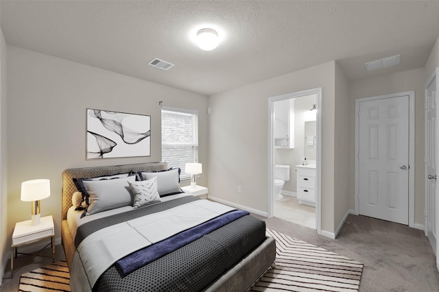 bedroom featuring light colored carpet, baseboards, and ensuite bath