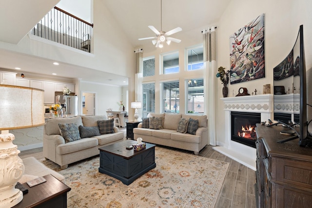 202 Bentwater Ln, Clute, TX 77531 - living room featuring a ceiling fan, a glass covered fireplace, wood finished floors, a towering ceiling, and baseboards