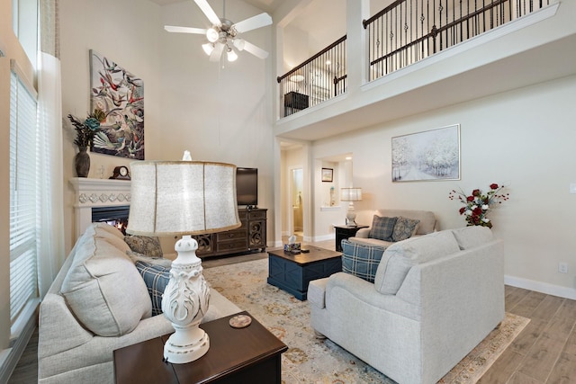 202 Bentwater Ln, Clute, TX 77531 - living area with a towering ceiling, a ceiling fan, baseboards, wood finished floors, and a glass covered fireplace