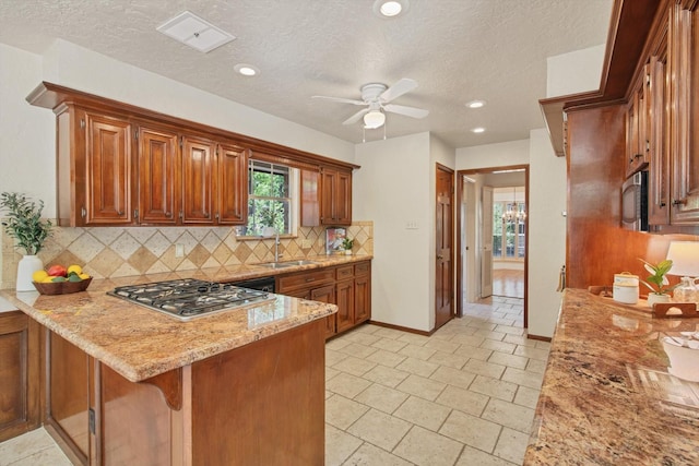 kitchen with appliances with stainless steel finishes, a sink, a peninsula, tasteful backsplash, and ceiling fan