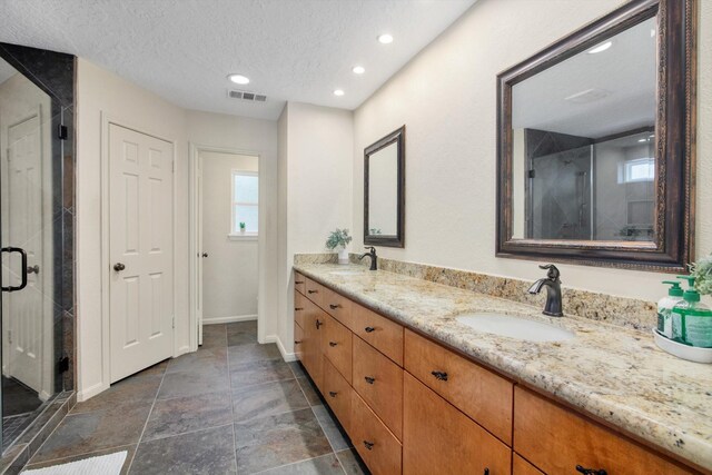 full bath with a shower stall, baseboards, double vanity, recessed lighting, and a textured ceiling
