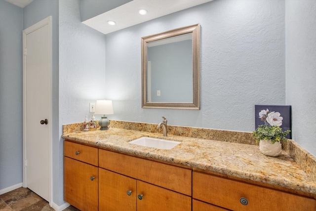 bathroom featuring vanity, baseboards, and a textured wall