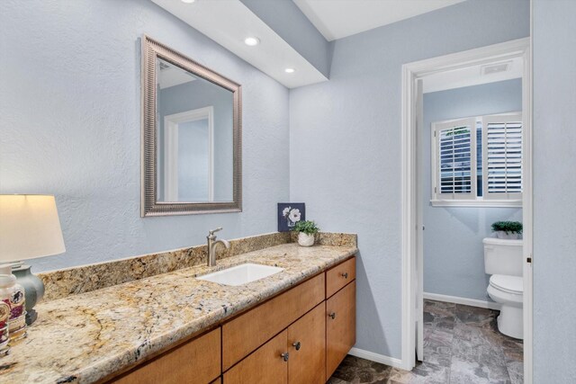 bathroom with vanity, toilet, and baseboards