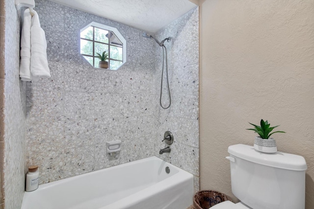 bathroom featuring washtub / shower combination, toilet, and a textured wall
