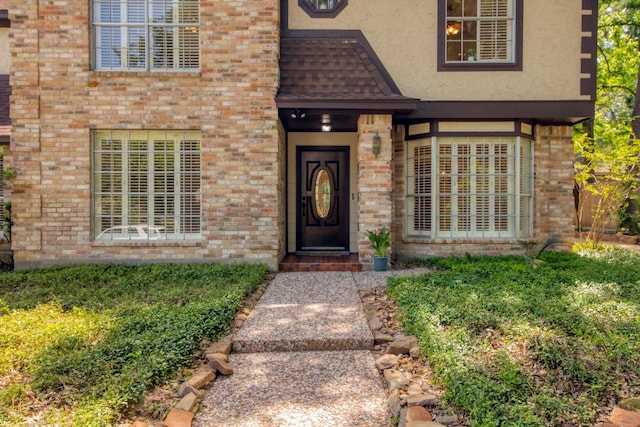 property entrance with brick siding and stucco siding