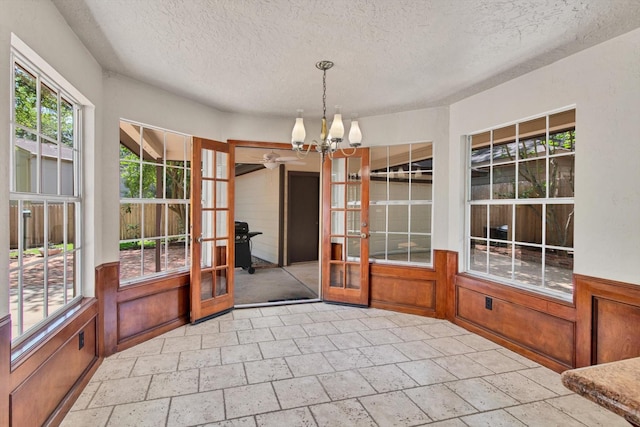 unfurnished sunroom with french doors and a chandelier