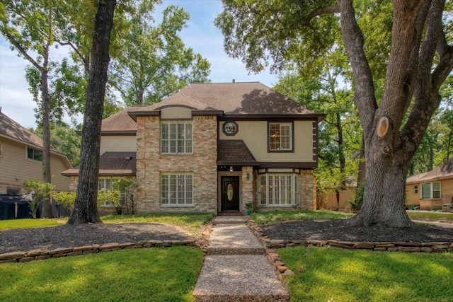 view of front of home with stucco siding, roof with shingles, and a front lawn