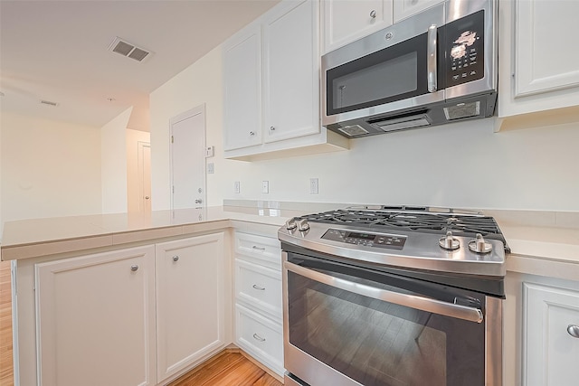 3722 Main Poplar Dr, Houston, TX 77025 - kitchen with stainless steel appliances, a peninsula, white cabinets, and light countertops