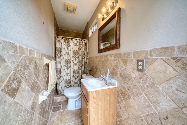 7810 Broken Arrow St, Baytown, TX 77521 - bathroom featuring tile walls, toilet, curtained shower, vanity, and stone finish flooring