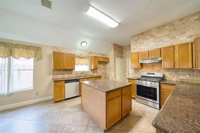 7810 Broken Arrow St, Baytown, TX 77521 - kitchen with stainless steel appliances, under cabinet range hood, lofted ceiling, light tile patterned flooring, and decorative backsplash