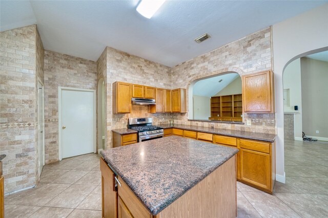 7810 Broken Arrow St, Baytown, TX 77521 - kitchen with stainless steel range with gas stovetop, under cabinet range hood, light tile patterned floors, and arched walkways