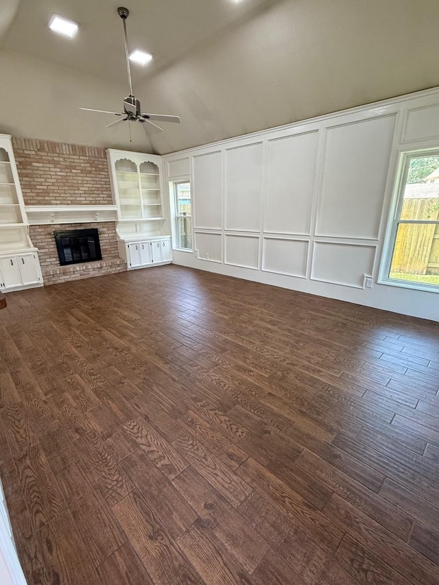13102 Lake Mist Dr, Cypress, TX 77429 - unfurnished living room with a decorative wall, a ceiling fan, dark wood-type flooring, vaulted ceiling, and a fireplace