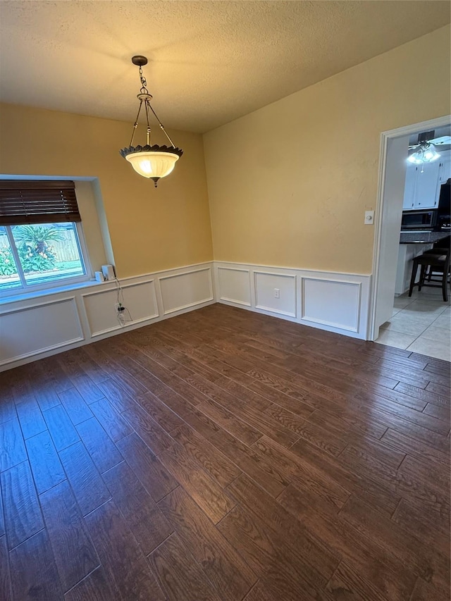 13102 Lake Mist Dr, Cypress, TX 77429 - empty room with dark wood-type flooring, a wainscoted wall, a decorative wall, and a textured ceiling