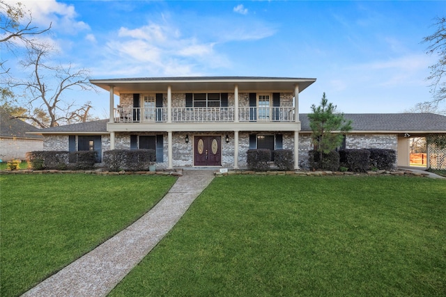 231 Corpus Dr, Magnolia, TX 77354 - view of front facade with a front lawn, brick siding, a balcony, and a porch