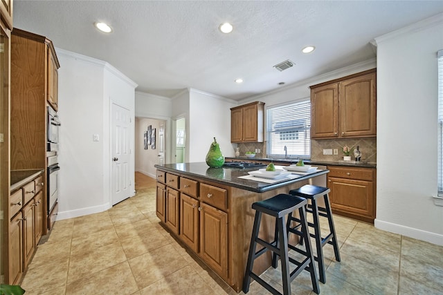 19715 Satinwood Trl, Humble, TX 77346 - kitchen with backsplash, a breakfast bar area, a center island, brown cabinets, and oven