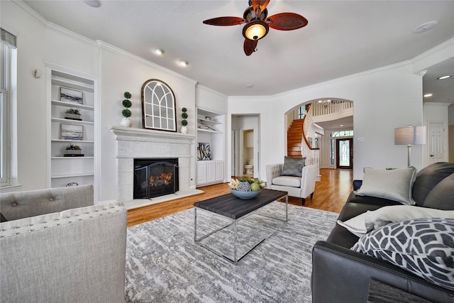 19715 Satinwood Trl, Humble, TX 77346 - living room with wood finished floors, ceiling fan, built in features, a glass covered fireplace, and ornamental molding