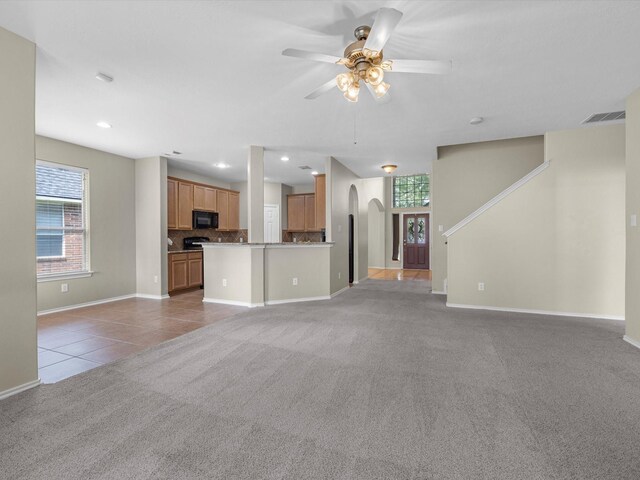 17510 Durham Ridge Ln, Humble, TX 77346 - unfurnished living room featuring light carpet, ceiling fan, baseboards, arched walkways, and light tile patterned floors