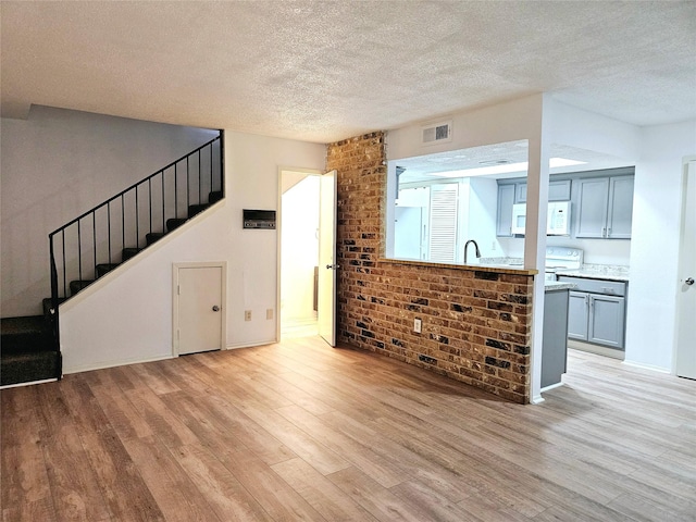 5670 Birchmont Dr Unit C, Houston, TX 77091 - unfurnished living room with light wood-style floors, a textured ceiling, stairway, and a sink