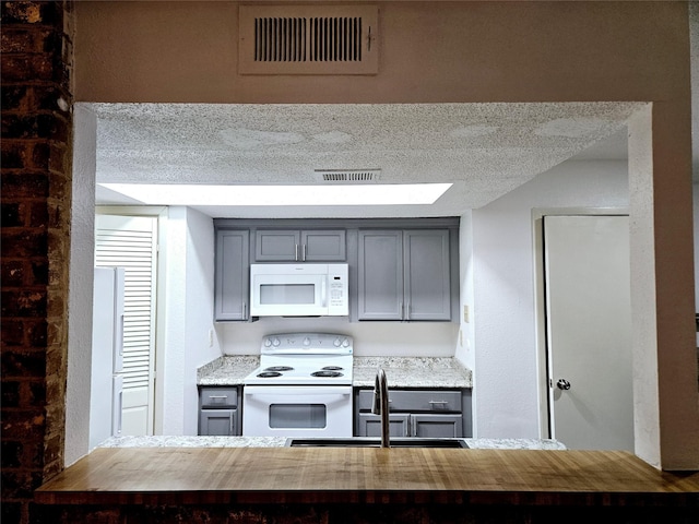 5670 Birchmont Dr Unit C, Houston, TX 77091 - kitchen with white appliances, a sink, gray cabinetry, and a textured ceiling