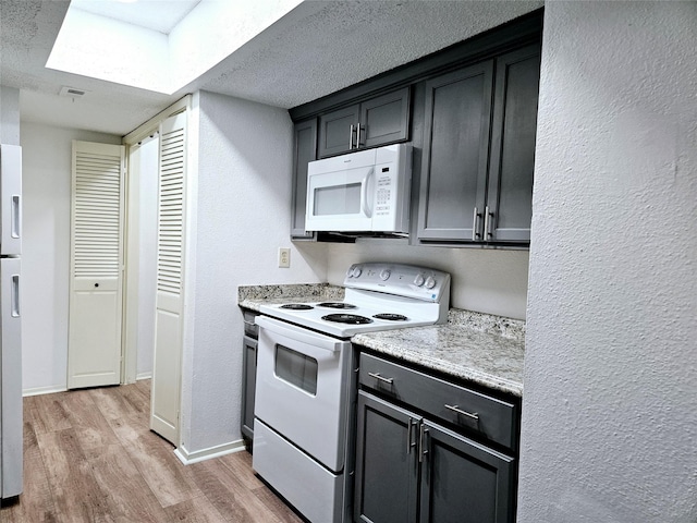 5670 Birchmont Dr Unit C, Houston, TX 77091 - kitchen with white appliances, light wood-style flooring, light countertops, baseboards, and a textured wall