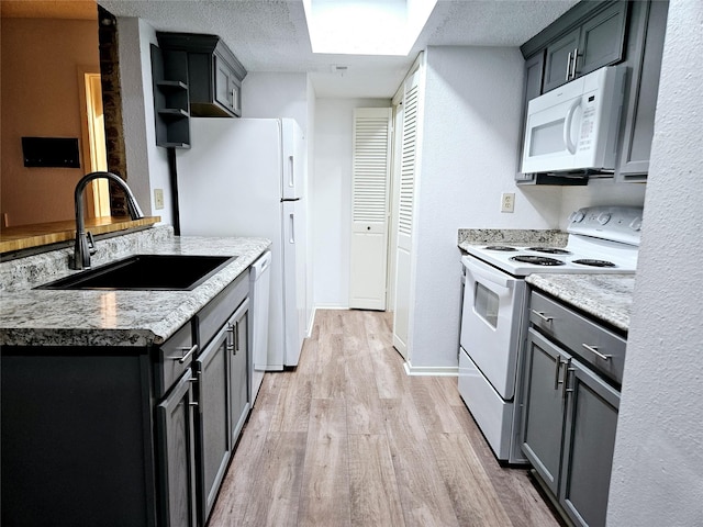 5670 Birchmont Dr Unit C, Houston, TX 77091 - kitchen with white appliances, a sink, light wood finished floors, a skylight, and baseboards