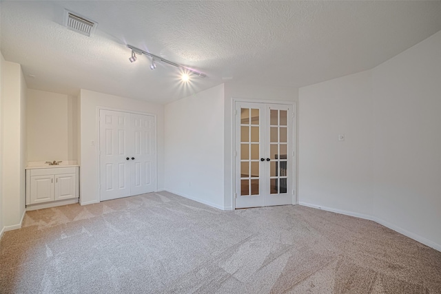 5918 Pendelton Place Dr, Sugar Land, TX 77479 - unfurnished room featuring french doors, rail lighting, light colored carpet, a textured ceiling, and baseboards