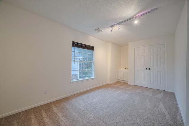 5918 Pendelton Place Dr, Sugar Land, TX 77479 - unfurnished bedroom featuring rail lighting, light colored carpet, baseboards, a textured ceiling, and a closet