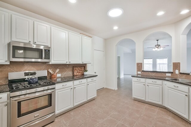 13507 Marblepointe Ln, Cypress, TX 77429 - kitchen with stainless steel appliances, arched walkways, a sink, white cabinetry, and recessed lighting