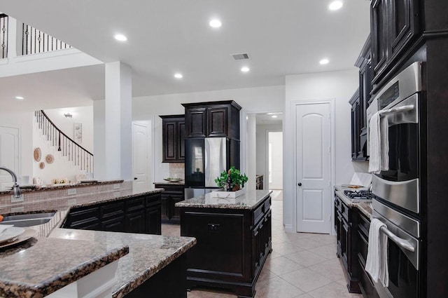 11307 Bentgrove Ln, Cypress, TX 77433 - kitchen with a sink, a center island with sink, appliances with stainless steel finishes, decorative backsplash, and light stone countertops