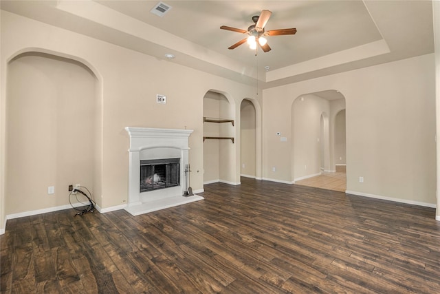 1938 Honey Laurel Dr, Conroe, TX 77304 - unfurnished living room featuring a tray ceiling, a ceiling fan, wood finished floors, and a fireplace with raised hearth