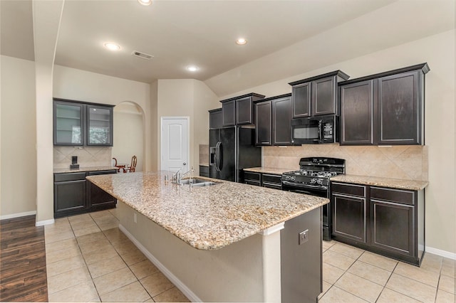 1938 Honey Laurel Dr, Conroe, TX 77304 - kitchen with black appliances, arched walkways, a kitchen island with sink, backsplash, and a sink